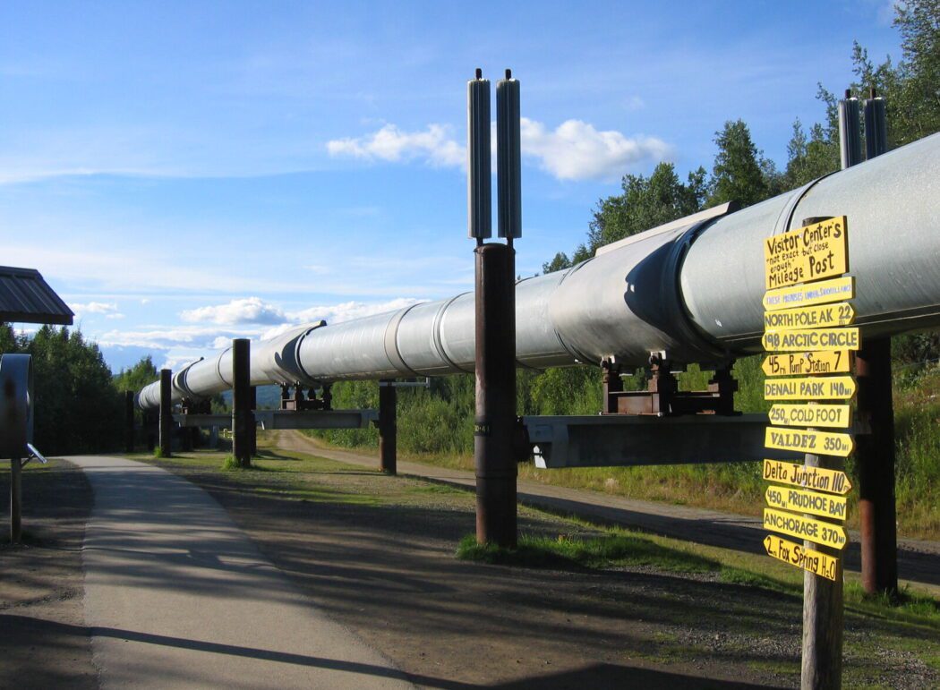 the Trans-Alaska Pipeline next to a walking path and directional signage