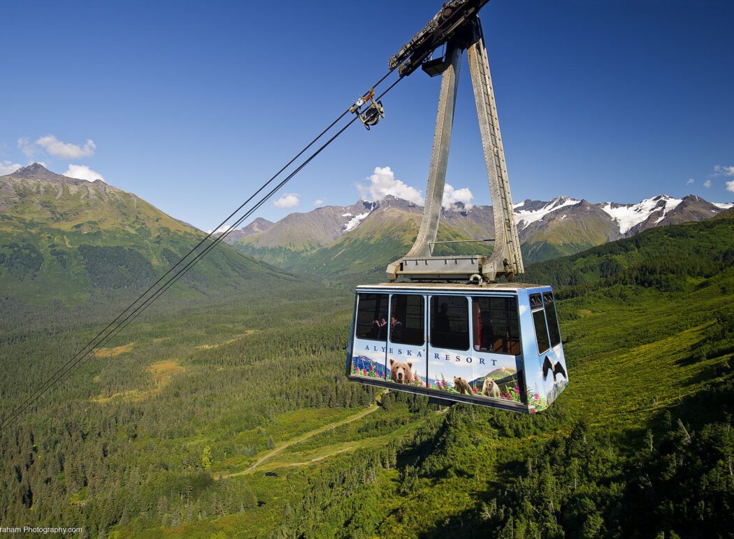 an aerial tram with the words "Alyeska Resort" in a mountainous landscape