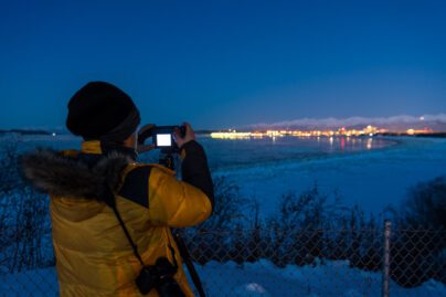 a person at night in winter taking a photo on a digital camera of the skyline of Anchorage, Alaska