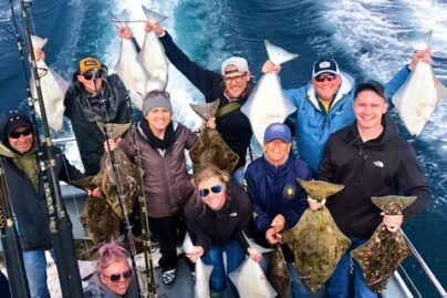 A group of people on a boat holding their caught halibut
