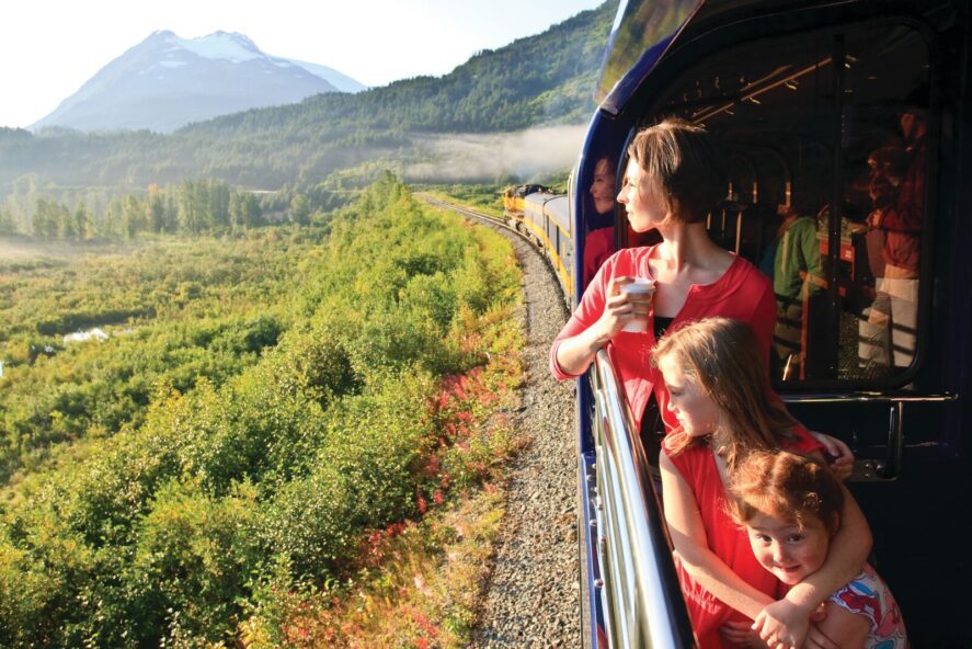 an adult and two children riding on the Alaska Railroad passenger train
