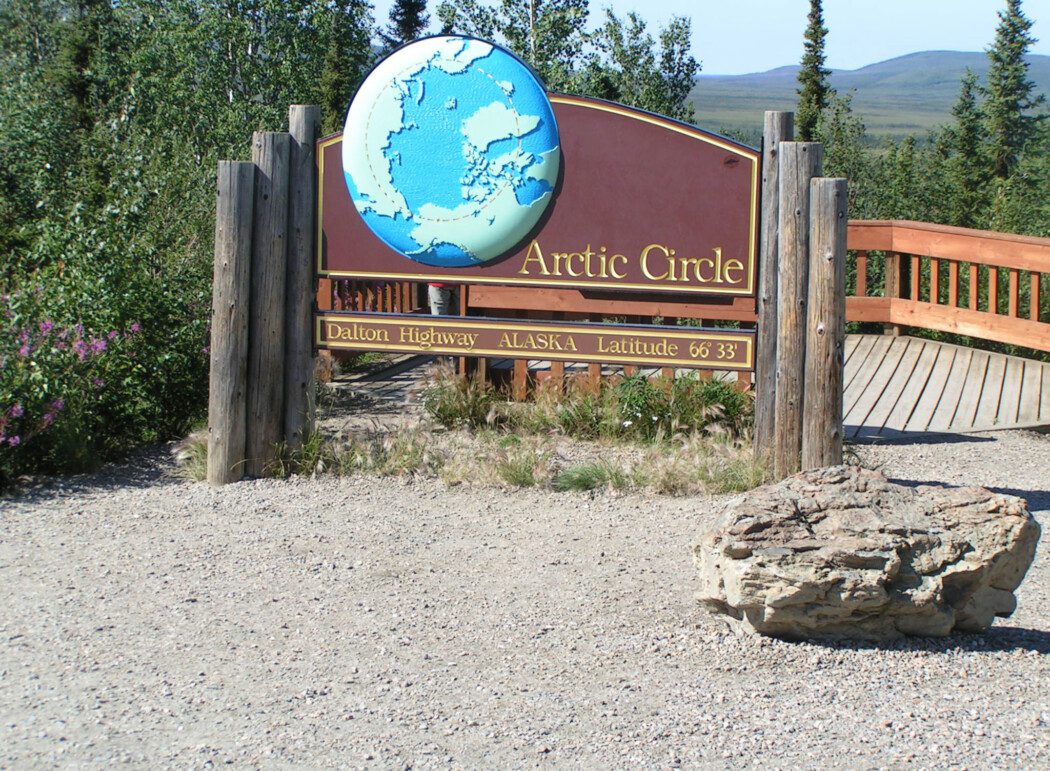 a wood sign reading "Arctic Circle, Dalton Highway, Alaska, Latitude 66°33'"