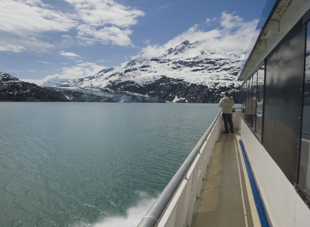 a person on the deck of a tour boat looking at a tidewater glacier