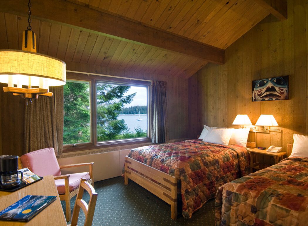 a hotel room with beds, furniture, coffee maker, and window views of Glacier Bay, Alaska