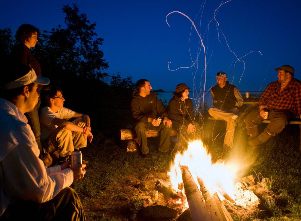 seven people sitting around a campfire at night