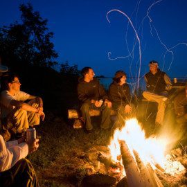 Guests of Redoubt Bay Lodge relax around a campfire.