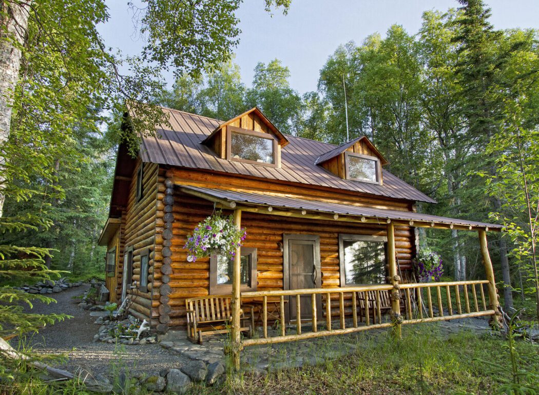 the exterior of a log cabin lodge set in a remote Alaskan wilderness