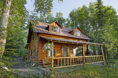 the exterior of a log cabin lodge set in a remote Alaskan wilderness