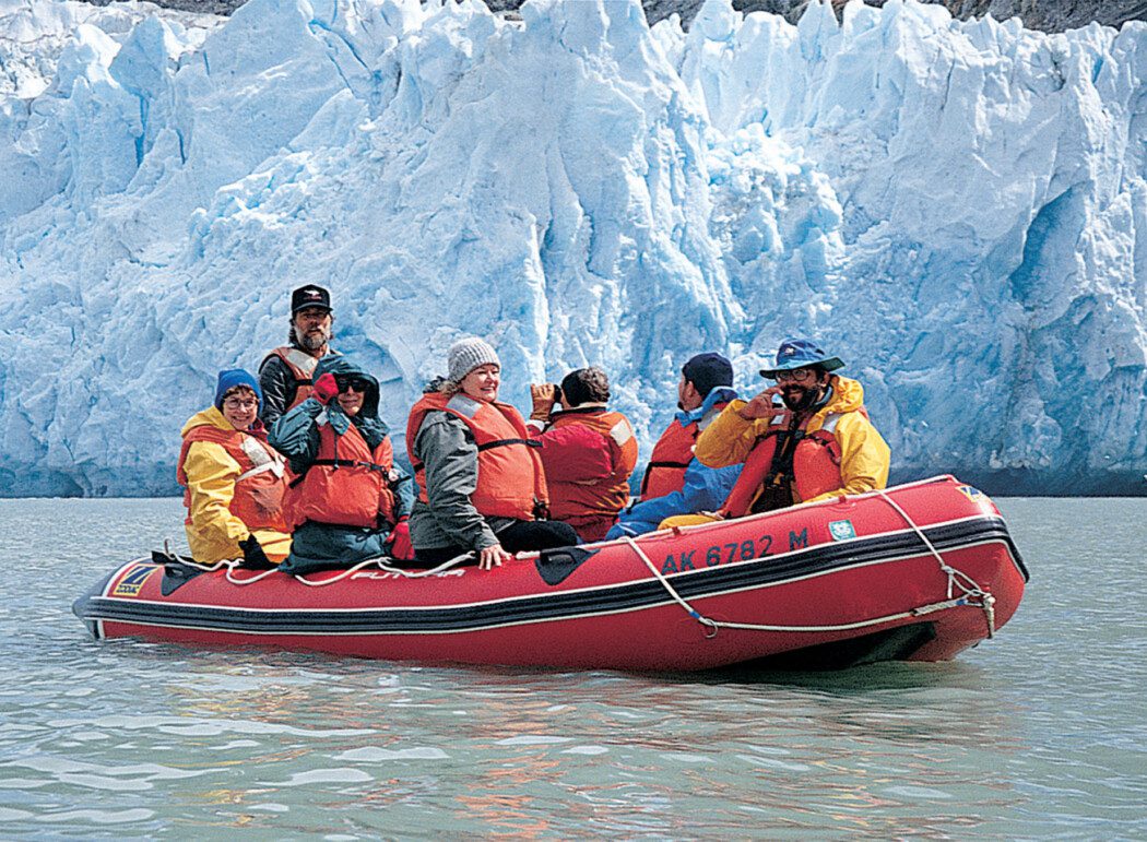 a group of people in a raft in front of a tidewater glacier
