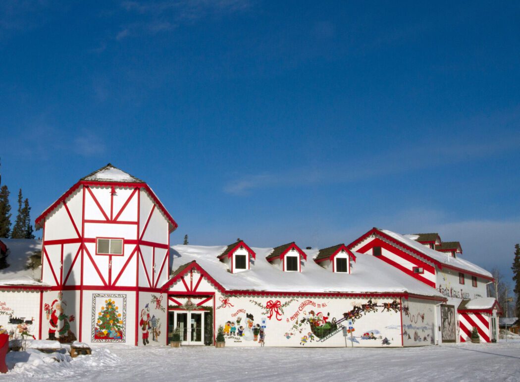 The red and white exterior of a building, with Christmas murals including Santa and his reindeer and children building a snowman
