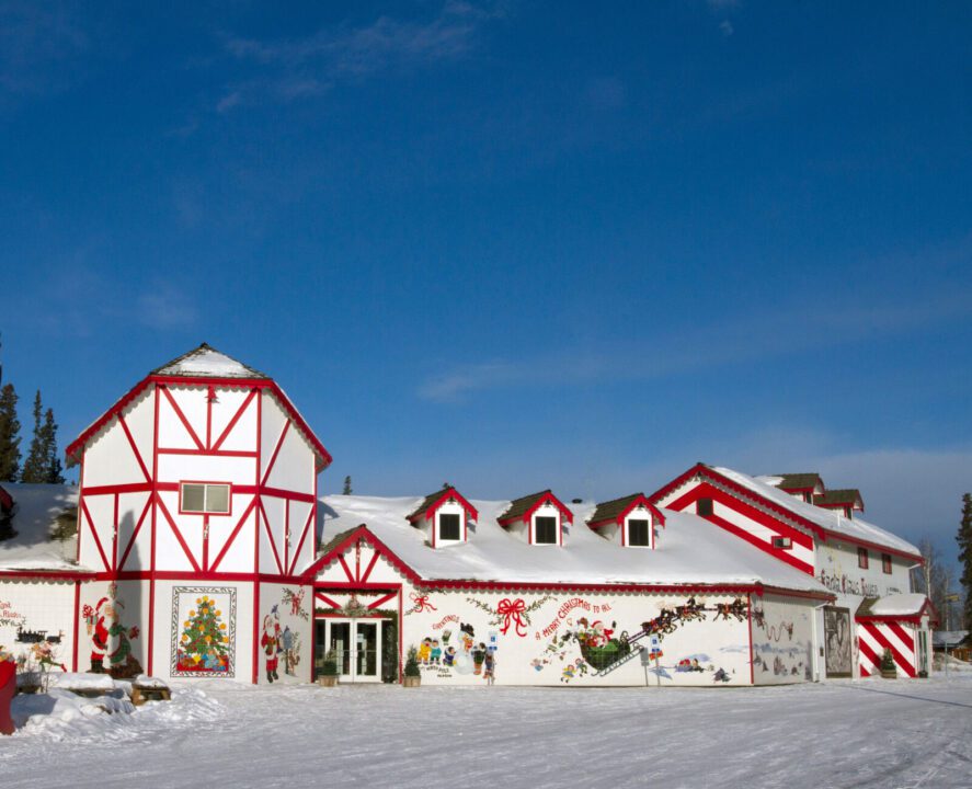 The red and white exterior of a building, with Christmas murals including Santa and his reindeer and children building a snowman