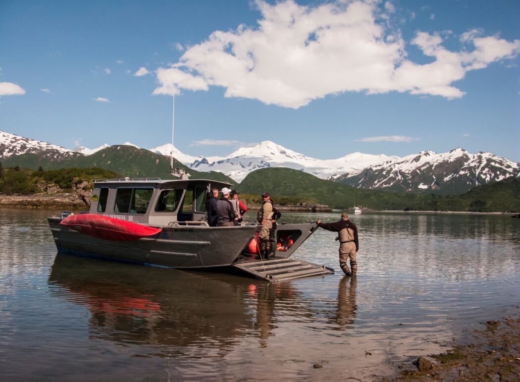 people on a boat with a front-loading ramp near shore in a remote part of Alaska