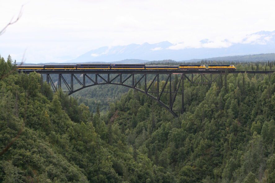 a passenger train travels across a bridge over a gulch