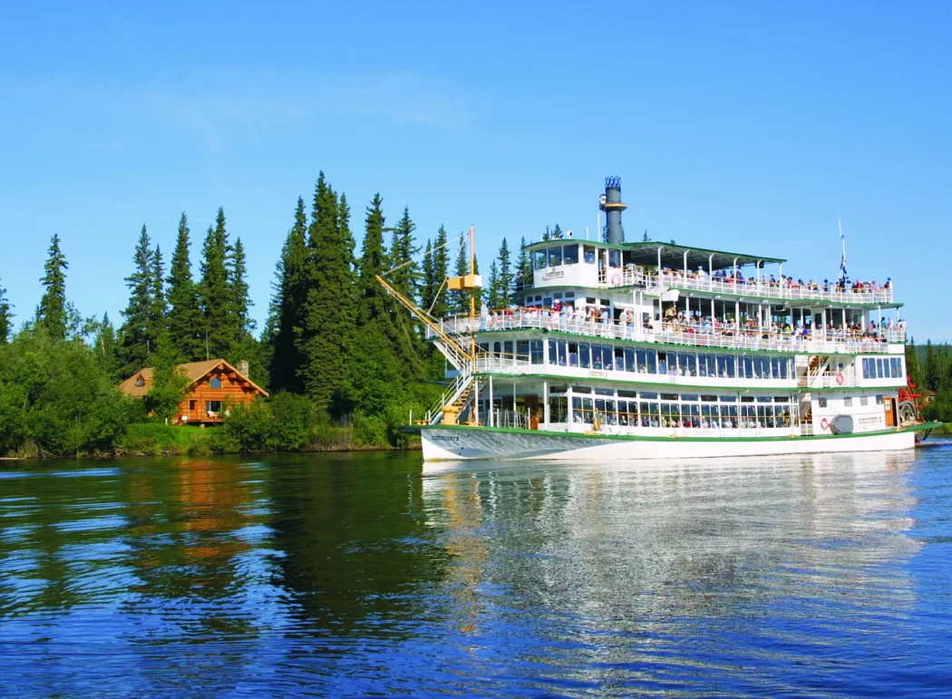 a sternwheeler river boat next to the bank of a river