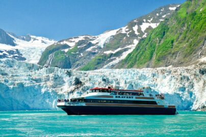 a catamaran labeled "Bravest" with tourists in front of a tidewater glacier
