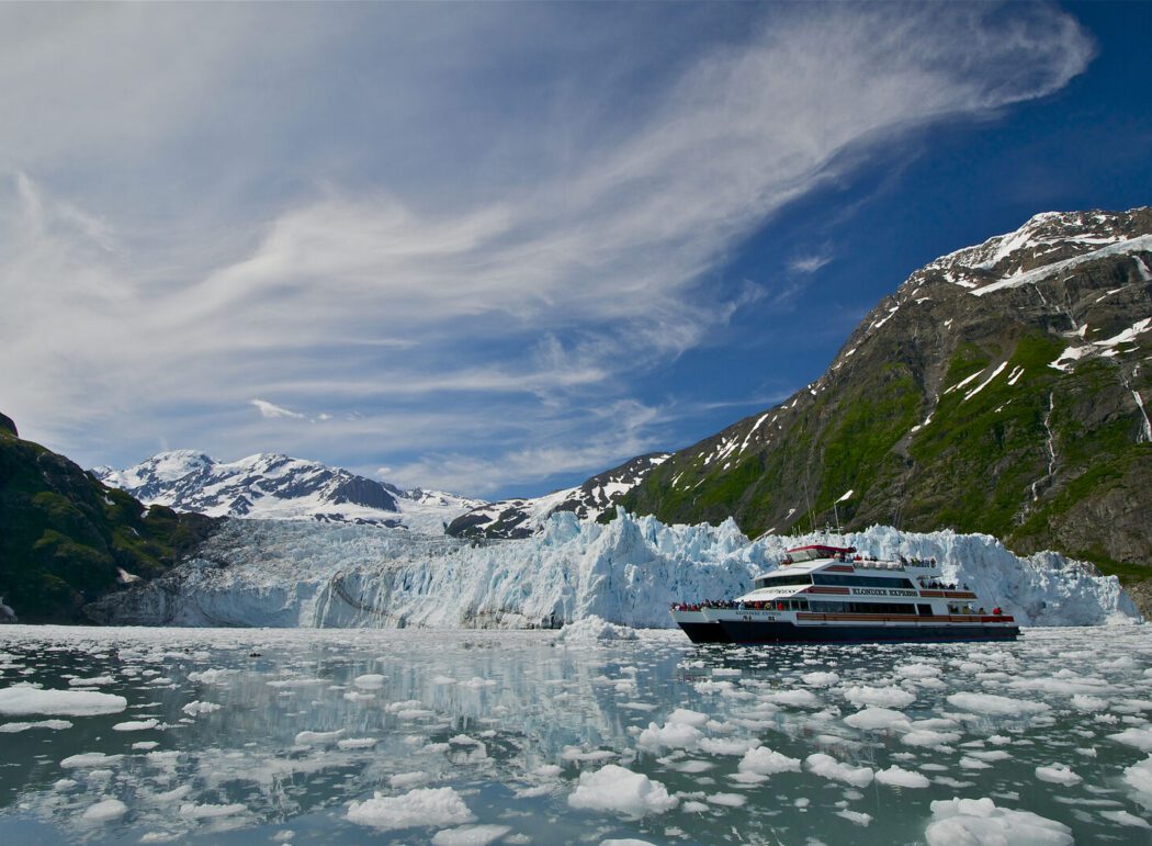 a catamaran labeled "Klondike Express" with tourists in front of a tidewater glacier
