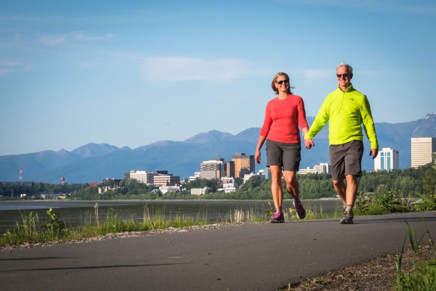 a couple holding hands while walking on a paved trail outside of Anchorage, Alaska