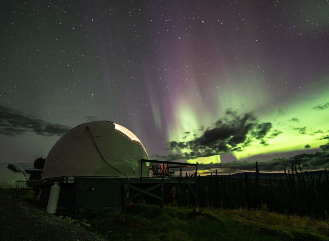 a fiberglass dome at night with aurora in the sky