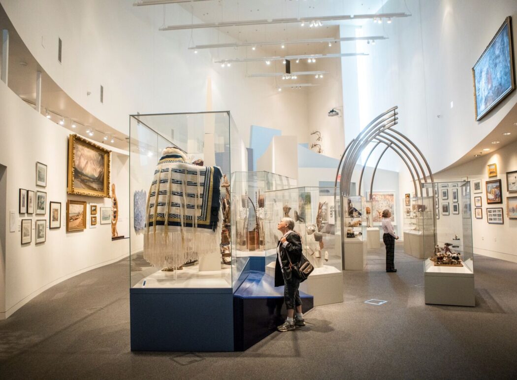 A museum gallery with artworks on the walls and objects on exhibit