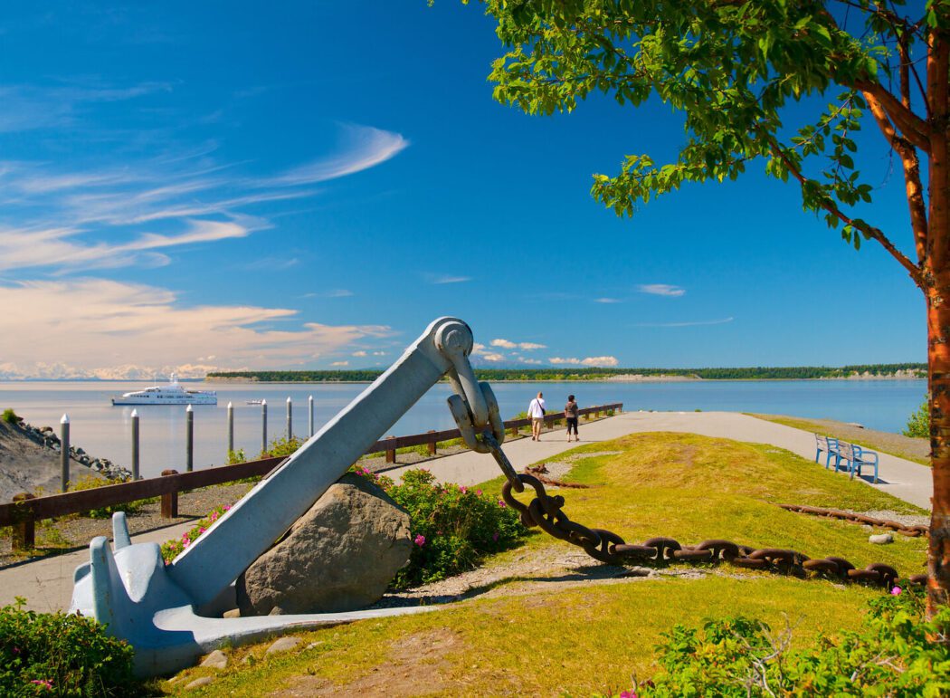 a ship anchor centered in a public park along a scenic waterfront