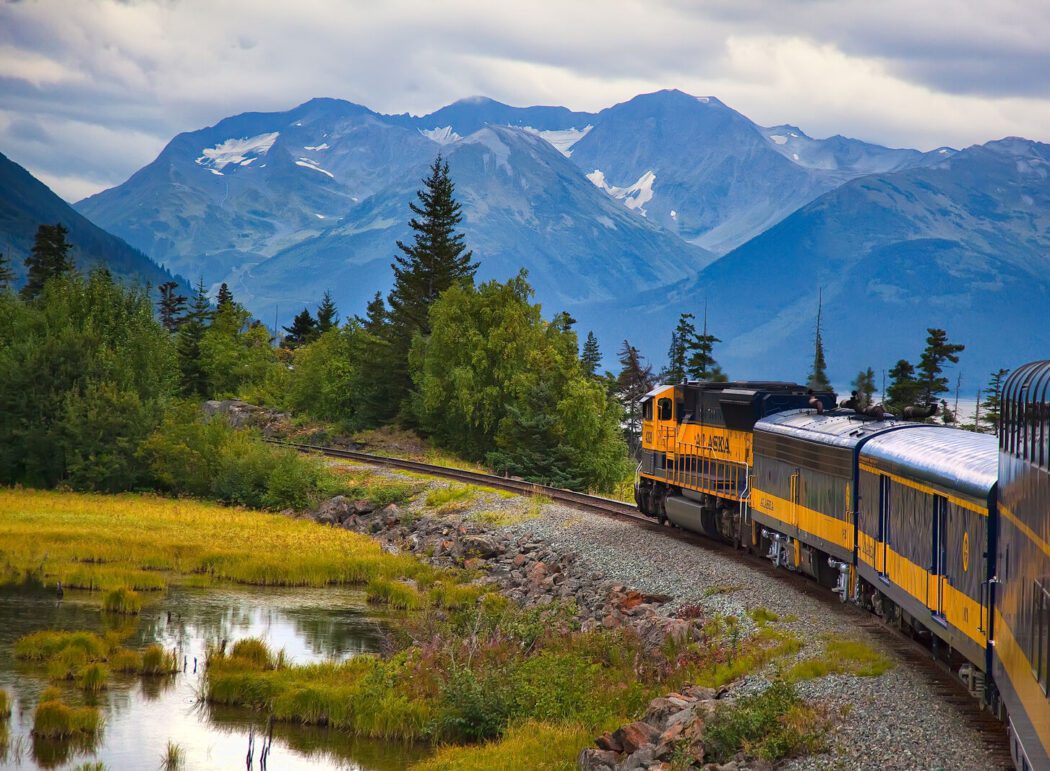 a passenger train travels through a forested and mountainous landscape