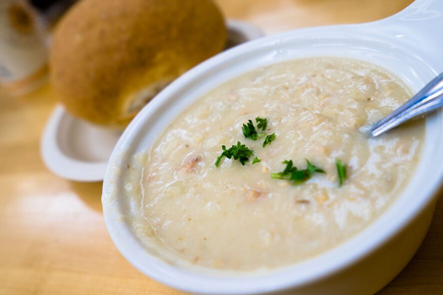 a bowl of chowder soup and a bread roll