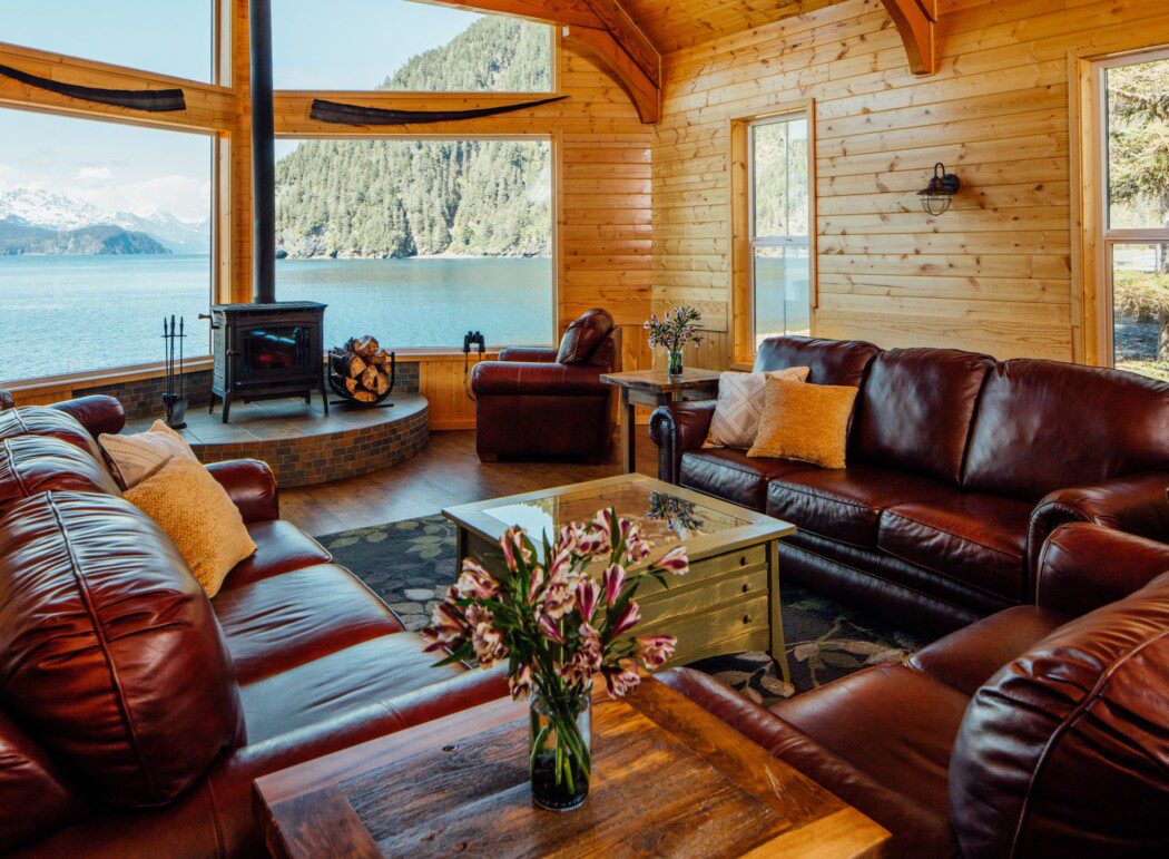 leather couches and a wood stove in a lodge with window views of Resurrection Bay