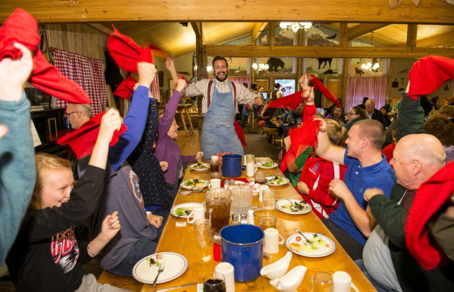 people sitting at a table eating dinner and enjoying a dinner theatre show