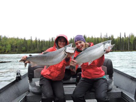 two people in a boat on a lake in Alaska holding up salmon fish