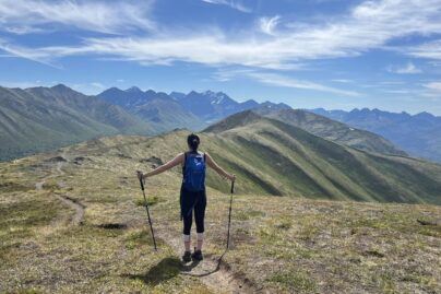 A person with trekking poles hiking along an alpine trail in Alaska