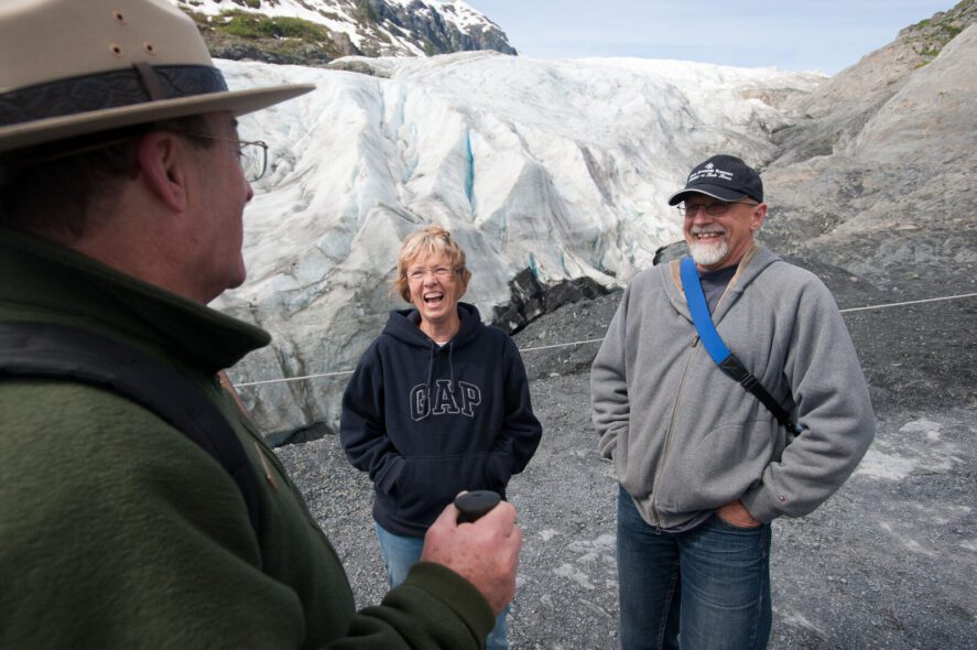 a couple talks to a park ranger in front of Exit Glacier in Kenai Fjords National Park