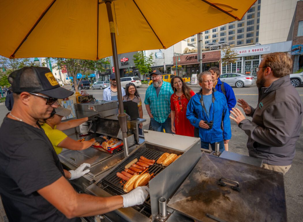 Guests on this Anchorage sightseeing tour taste a reindeer hot dog.